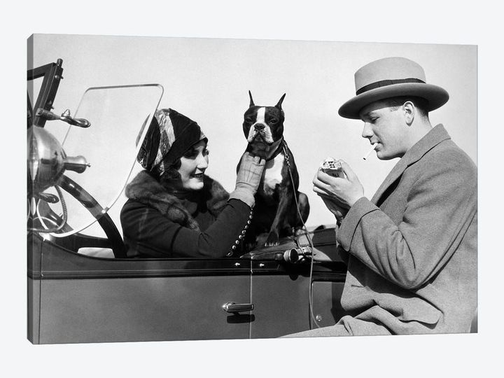 1920s Woman Sitting In Driver's Seat Convertible Car With Boxer Dog Man Lighting Cigarette