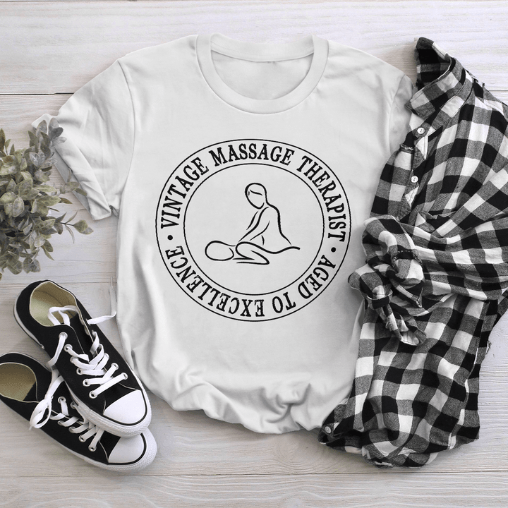 White massage therapist t-shirt with graphic design depicting a person getting a massage in a circle, accompanied by the quote 'Massage is a great way to relax and de-stress'.