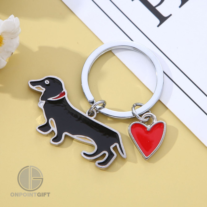 Express your love for adorable Dachshunds with our Cute Sausage Dog Keychain. This charming accessory is not just a keychain; it's a declaration of affection for these lovable pups.  Featuring a heart and bone-shaped charm, this keychain showcases your passion for Dachshunds with the phrase "I Love Dachshunds." It's the perfect way to carry your admiration for these sausage dogs with you wherever you go.  Crafted with attention to detail and made from high-quality materials, this keychain is not only stylish but also durable. Attach it to your keys, bag, or backpack for a touch of canine charm that will spark conversations and connect you with fellow Dachshund enthusiasts.  This Cute Sausage Dog Keychain is an ideal gift for any dog lover or a delightful addition to your own collection of animal-themed accessories. Show the world your love for Dachshunds and let this keychain be a daily reminder of the joy and affection these dogs bring into your life.
