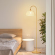 This picture shows a vintage simple rattan led floor lamp near the bed.