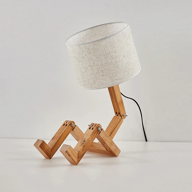 This picture shows a wooden robot shape creative table lamp in beige color.
