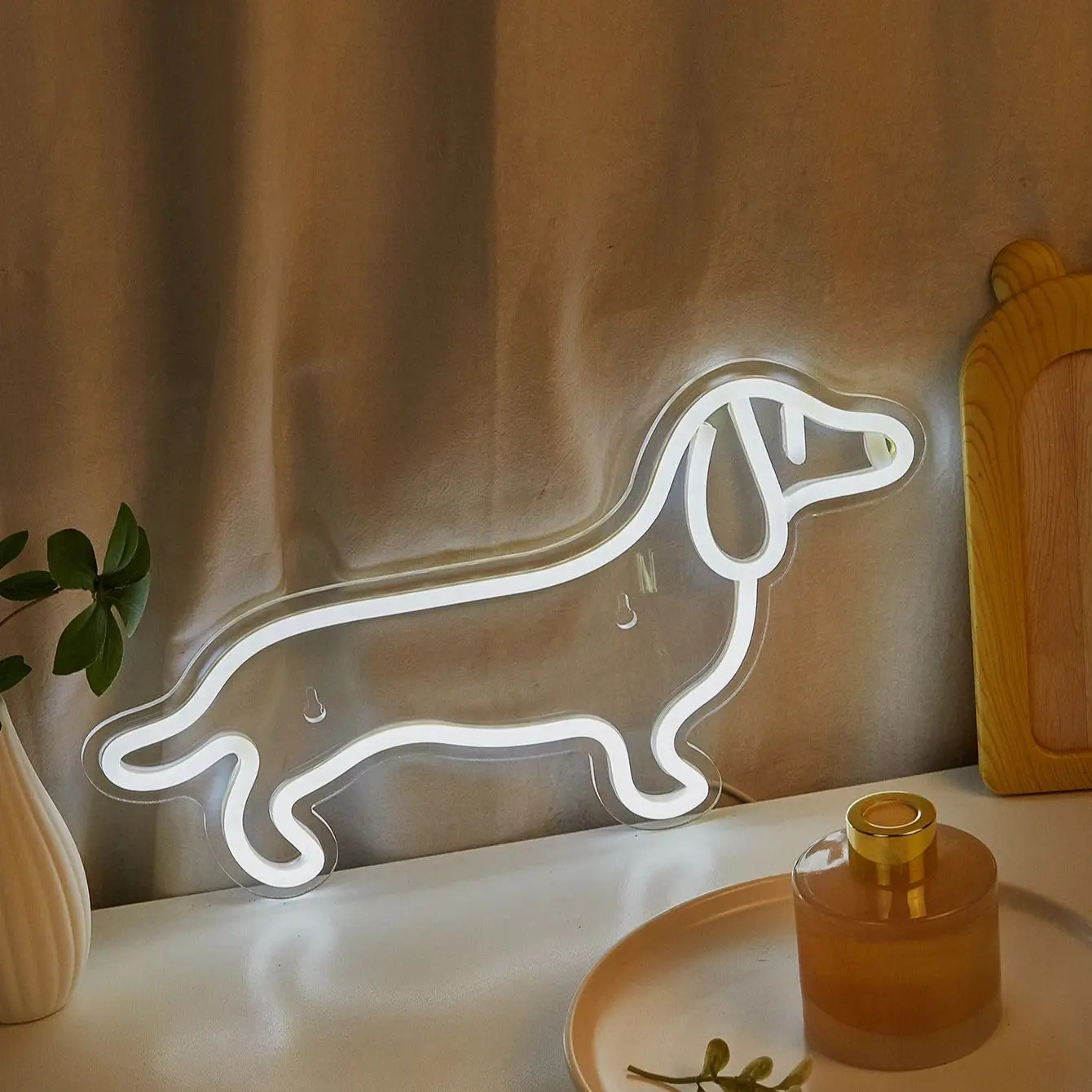 Aesthetic white Dachshund neon light resting on a nightstand beside home decor