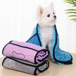 Super Absorbent Dog Bathrobe for Golden Retrievers — white dog wearing the blue robe, sitting behind rolled pink and grey robes