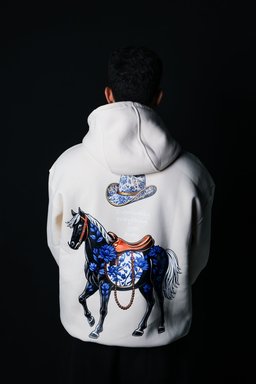 Safar hoodie in beige worn by a model – black horse with blue florals and cowboy hat print by QADIM