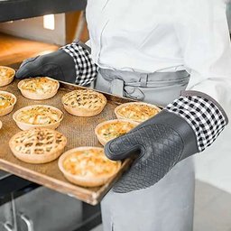 Close up of hands wearing non-slip silicone oven mitts holding hot plate in kitchen