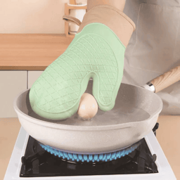 Woman holding hot frying pan with mint green silicone anti-scalding kitchen glove on gas stove