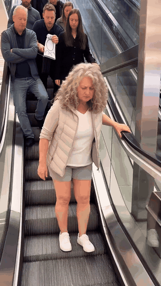 Woman wincing as she steps down an escalator