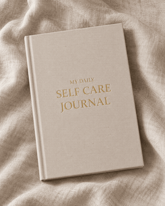 The journal, a sand-colored linen hardcover with gold lettering, lying on linen fabric.
