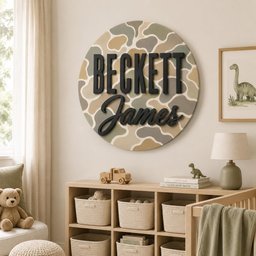 May include: A circular wall sign featuring a camouflage pattern in shades of tan, olive green, and cream. The sign displays the name Beckett in a bold, black sans-serif font, with the name James in a black, cursive script font layered on top.