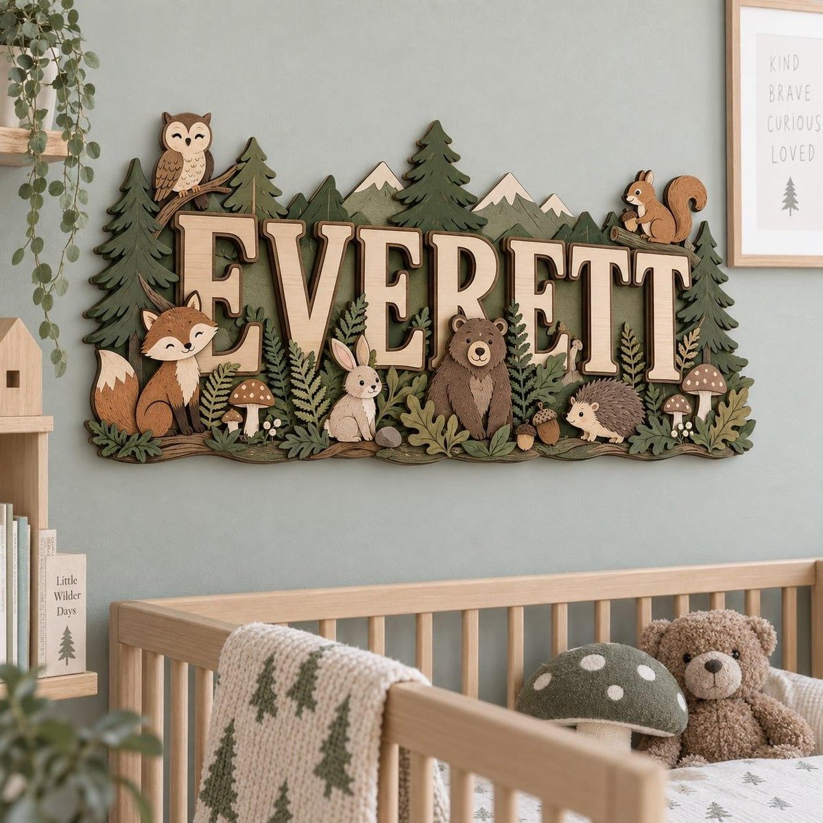 May include: A wooden wall sign featuring the name EVERETT in large capital letters, surrounded by layered cutouts of a forest scene including an owl, fox, rabbit, bear, squirrel, hedgehog, mushrooms, pine trees, and mountain peaks in green and brown.
