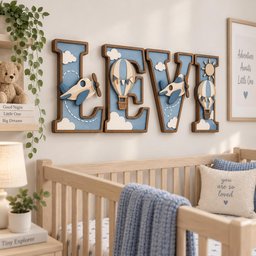 May include: Four large wooden letters spelling LEVI, featuring a blue background with layered 3D cutouts of airplanes, hot air balloons, clouds, and a sun. The letters have dark brown borders and are mounted on a wall above a wooden crib.