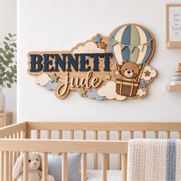 May include: A wooden wall sign featuring the name BENNETT Jude in dark blue and light wood lettering. The design includes a hot air balloon with a brown teddy bear in the basket, surrounded by light blue, cream, and green clouds and stars.
