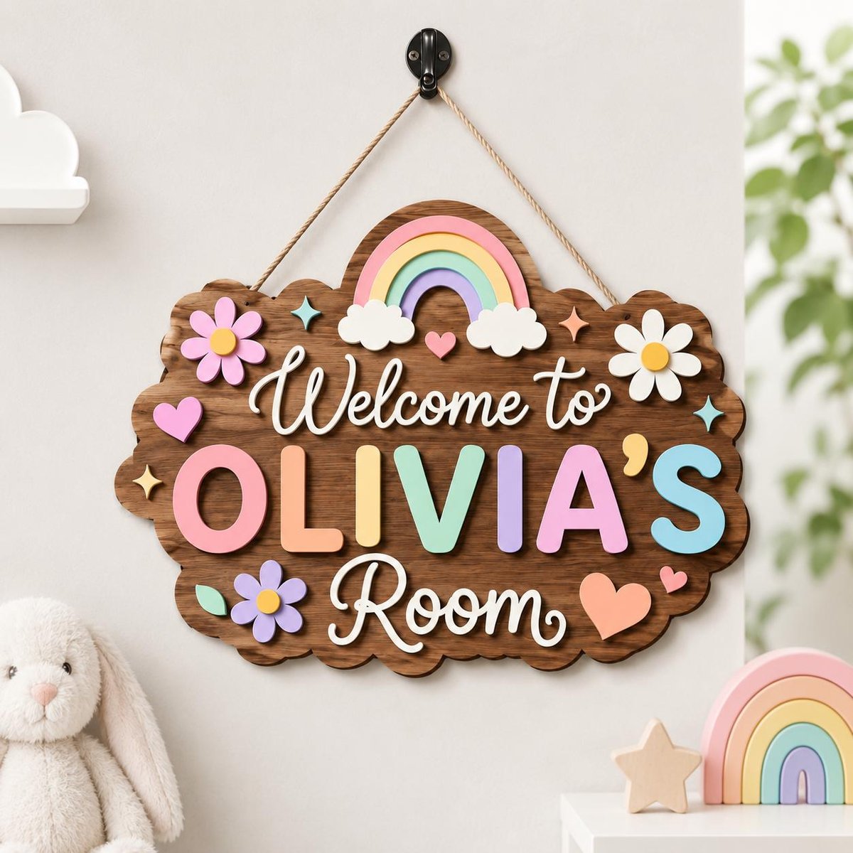 May include: A dark wood wall sign with a hanging rope featuring the text Welcome to OLIVIA'S Room in white and pastel-colored 3D letters. The sign is decorated with a pastel rainbow, white clouds, pink and white flowers, and small hearts.