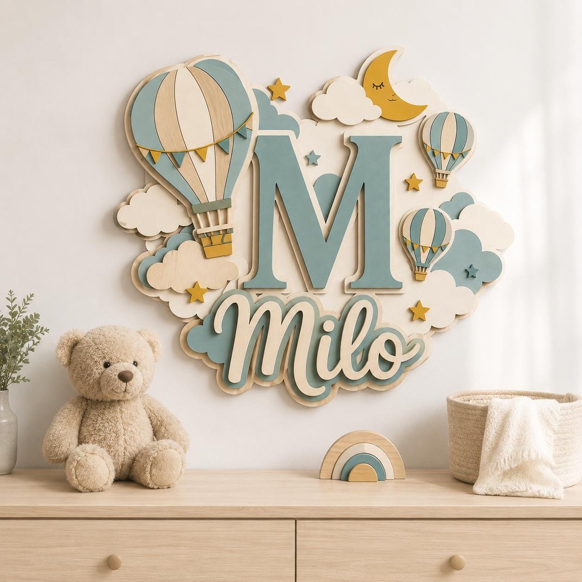 May include: A wall-mounted wooden sign featuring the letter M and the name Milo in script, decorated with hot air balloons, clouds, a crescent moon, and stars in shades of blue, cream, and yellow. The sign is layered with a 3D effect.