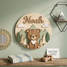 May include: A wooden nursery wall decor piece featuring a bear, mountains, and trees. The name "Noah" is displayed above the bear. The sign is round and has a natural wood finish. White clouds are also included in the design. A small sign says "ADVENTURE AWAITS".