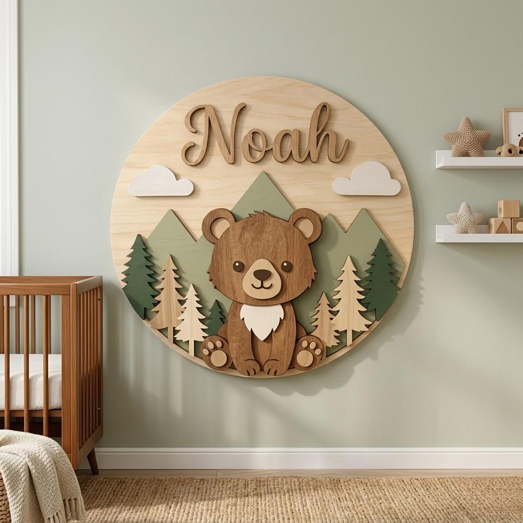 May include: A wooden wall decoration featuring a bear, mountains, trees, and clouds. The name "Noah" is displayed in a cursive font. The bear is brown with a white chest. The mountains are green, and the trees are various shades of green and brown.