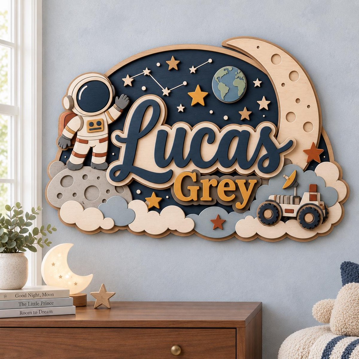 May include: A layered wooden wall sign featuring the name Lucas Grey in dark blue and gold lettering. The design includes a space theme with an astronaut, a crescent moon, a planet, stars, clouds, and a rover vehicle in shades of blue and tan.