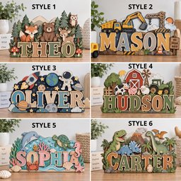 May include: Six wooden name signs featuring layered designs: a forest with animals, a construction site with the name MASON, a space theme with the name OLIVER, a farm scene with the name HUDSON, an ocean scene with the name SOPHIA, and a dinosaur scene with the name CARTER.