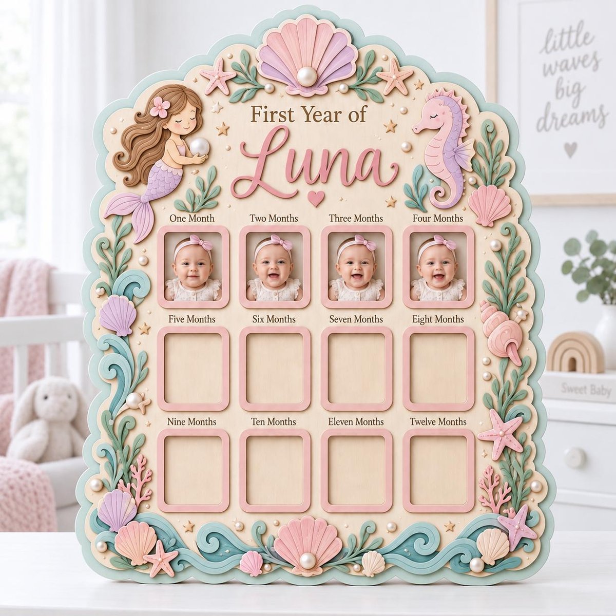 May include: A wooden baby milestone photo board titled First Year of Luna with twelve rectangular frames. The board features pastel-colored mermaid, seahorse, and seashell decorations with pearl accents. Four photos of a baby are displayed.