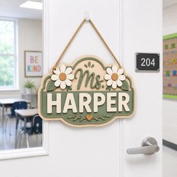 May include: A wooden hanging sign with a light wood border and a sage green center. The sign features the text Ms. HARPER in raised white lettering, decorated with two white daisies with yellow centers, green leaves, and a small orange heart.