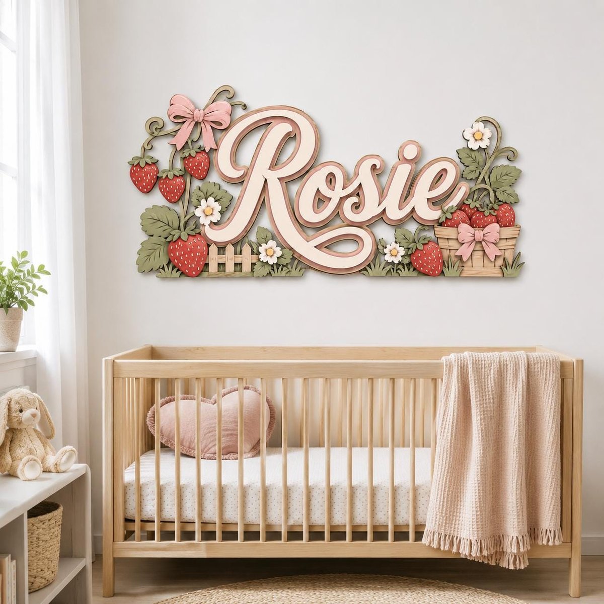 May include: A decorative wooden wall sign featuring the name Rosie in large cursive script, surrounded by layered strawberry plants, white flowers, a small picket fence, and a woven basket filled with strawberries, all accented with pink bows.