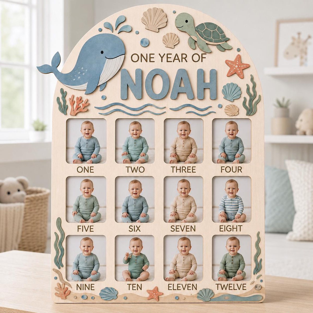May include: An arched wooden photo frame featuring a sea-themed design with a blue whale, a green turtle, seashells, and coral. The board displays the text "ONE YEAR OF NOAH" and includes twelve rectangular photo slots labeled one through twelve.