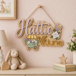 May include: A wooden wall sign featuring the name Hattie in purple script and the month June in yellow block letters. The sign includes a green flower cart, a yellow honeycomb with bees, and white floral accents, all suspended by a brown twine rope.