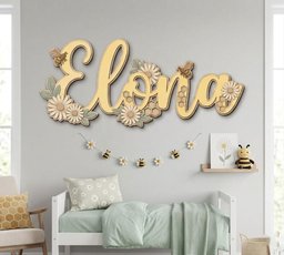 May include: A wall-mounted wooden sign displaying the name Elona in large cursive yellow letters. The sign is decorated with layered wooden daisies, green leaves, small honeycombs, and two bees attached to the letters in a light color palette.