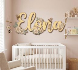 May include: A custom wooden wall sign featuring the name Elona in a cursive script, decorated with layered wooden daisies, green leaves, honeycomb patterns, and small bees. The sign is mounted on a light pink wall above a white crib.
