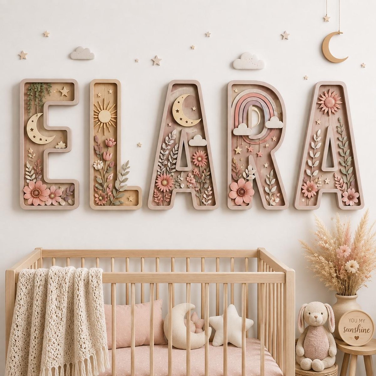 May include: Five large wooden letters spelling ELARA mounted on a wall, each featuring intricate 3D cutouts of moons, suns, rainbows, clouds, stars, and floral arrangements in soft pastel pink, beige, and muted green tones for nursery decor.