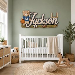 May include: A custom wooden wall sign featuring the name Jackson in large script lettering, accompanied by a cartoon bear wearing a blue jersey with the number 23, a basketball, a soccer ball, a football, and a gold-colored goal post.
